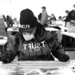 A worker at the Brooklyn Navy Yard produces disposable face shields for healthcare workers during the COVID-19 pandemic. The collaboration between businesses in the Yard to create PPE during this critical time inspired the creation of UU's Pull City—a platform designed to help business communities build sustainable local supply chains, supported by advancements in automation and machine learning.